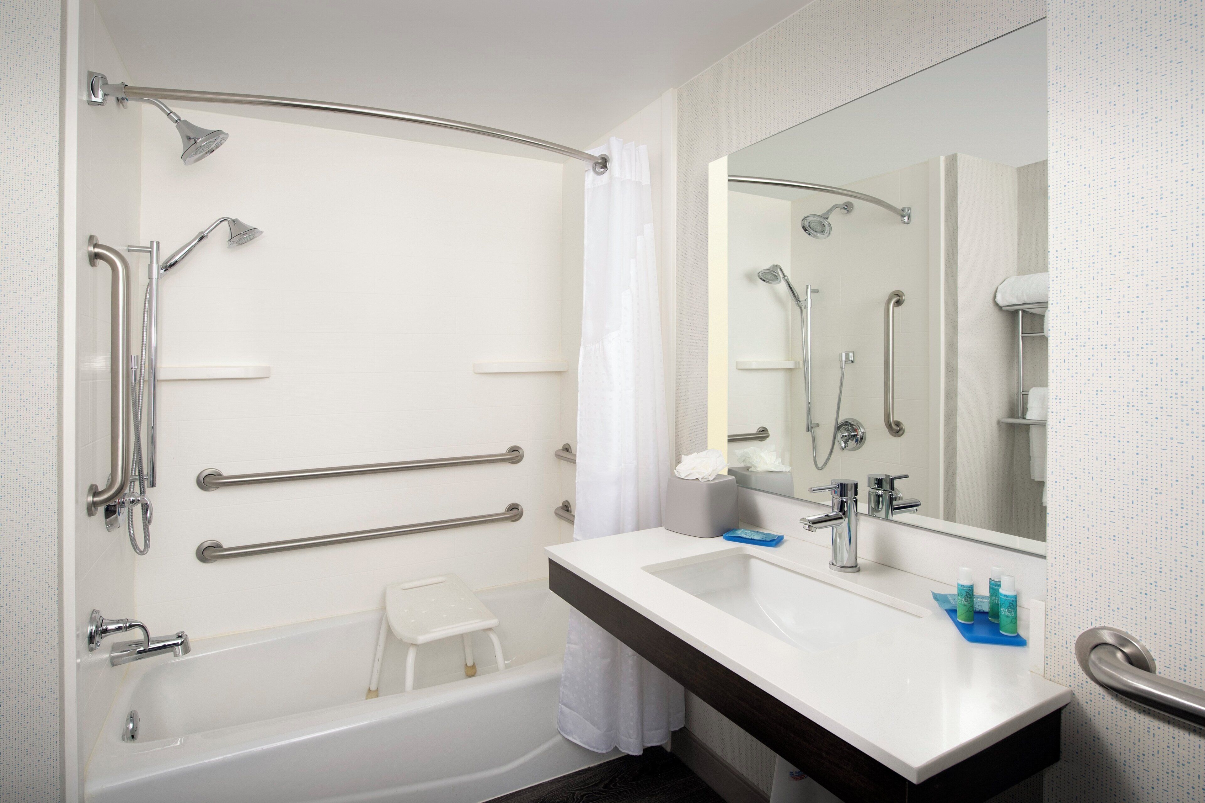 A modern bathroom with a bathtub, shower, and a large mirror.