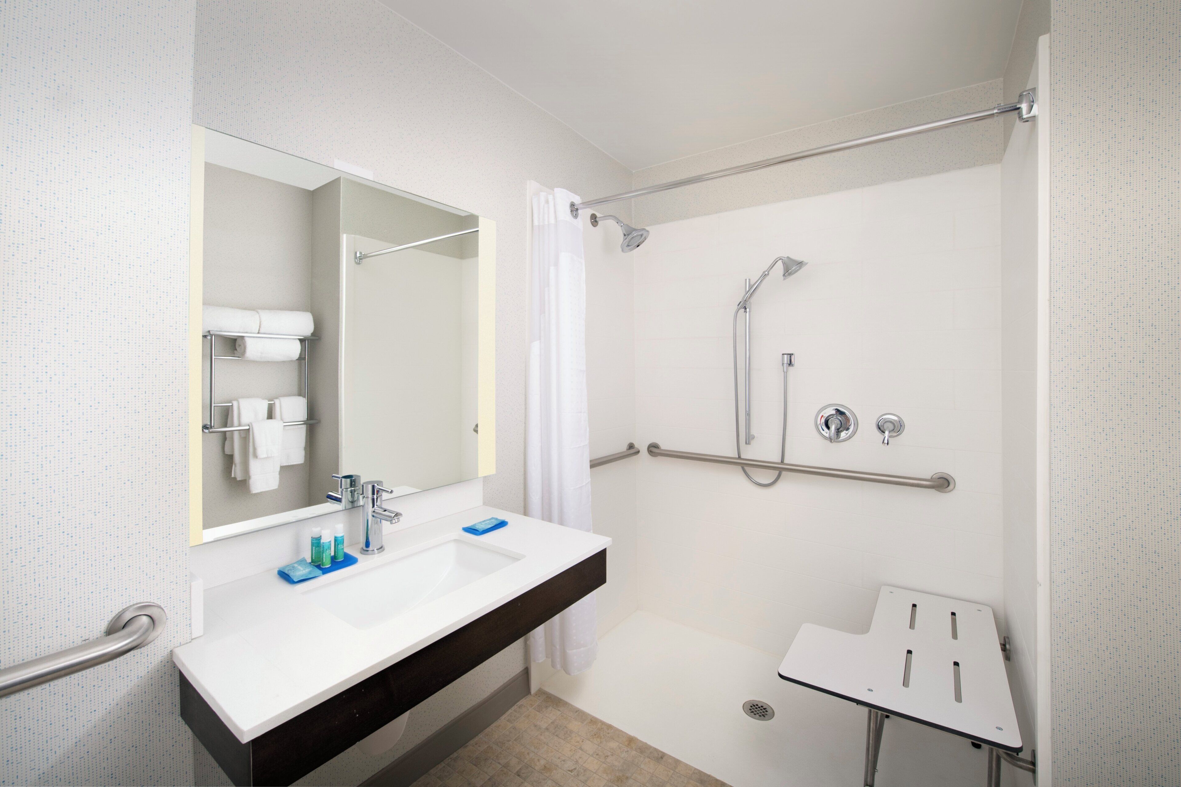 A modern bathroom with a white sink, mirror, and shower area.