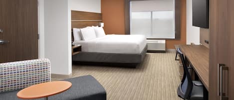 A hotel room with a bed, a desk, a TV, a sofa, and a small table.