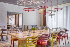Enjoy a comfortable dining experience in this stylish space, featuring a long table and plush chairs.