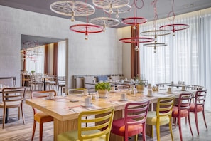 Enjoy a comfortable dining experience in this stylish space, featuring a long table and plush chairs.