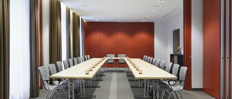 A conference room with a long table, chairs, and a red accent wall.