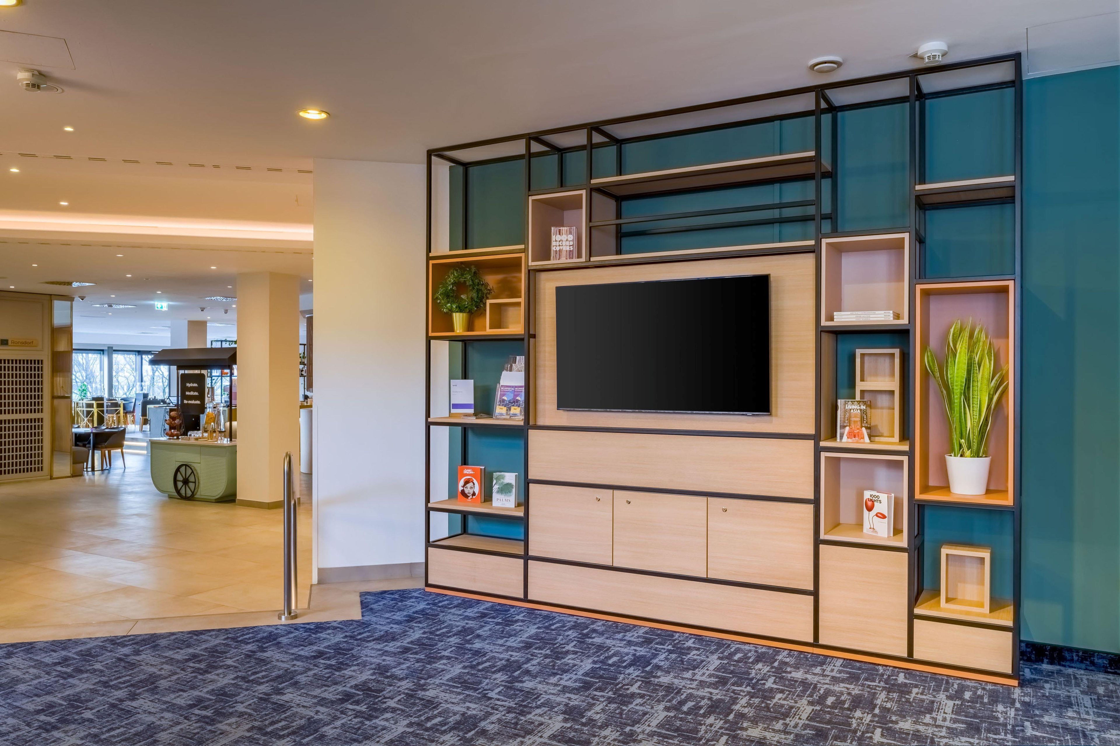 A modern interior with a flat-screen TV mounted on a wall, surrounded by shelves with various items.