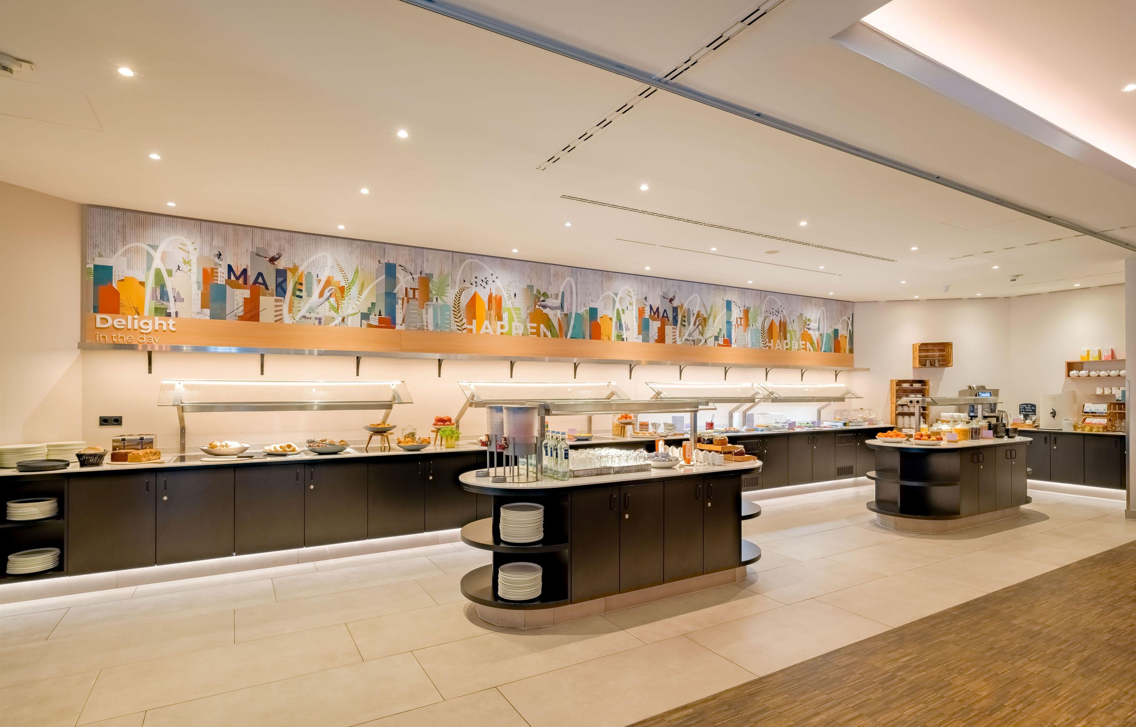 A modern breakfast buffet with multiple serving stations, a large cityscape mural on the wall, and a clean, contemporary design.