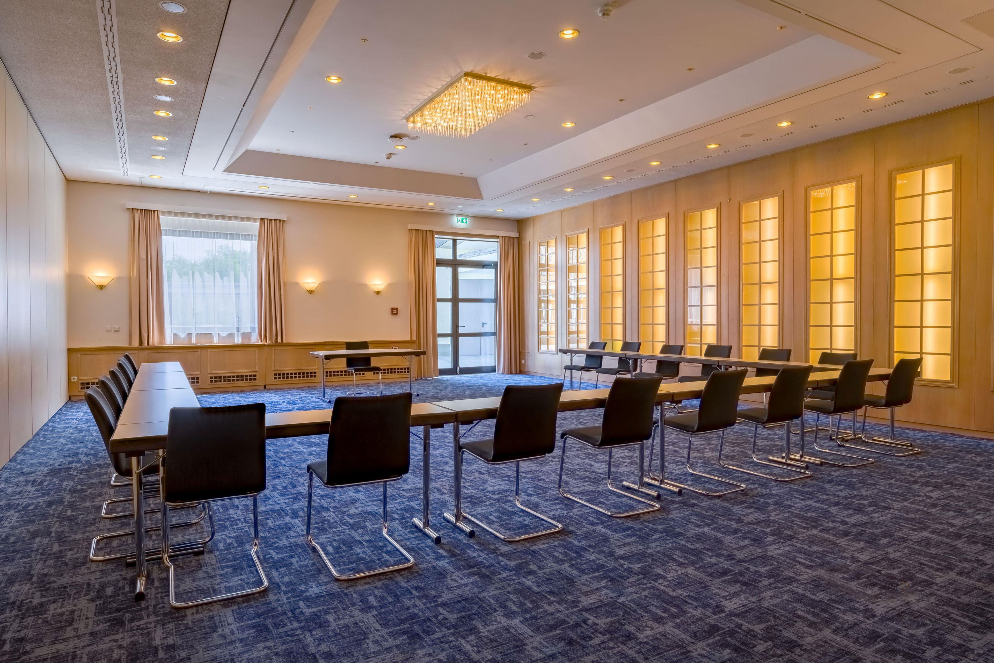 A conference room with a long table, chairs, and a carpeted floor.