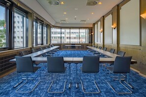 A conference room with a long table and chairs, large windows, and a blue carpet. - Spark by Hilton Wuppertal City Centre (Wuppertal)