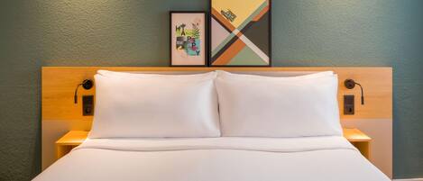 A neatly made bed with white linens, a wooden headboard, and two bedside tables with lamps.