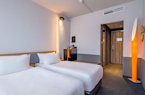 A hotel room with two beds, a bedside table, a mirror, and a door leading to another room. - Spark by Hilton Wuppertal City Centre (Wuppertal)