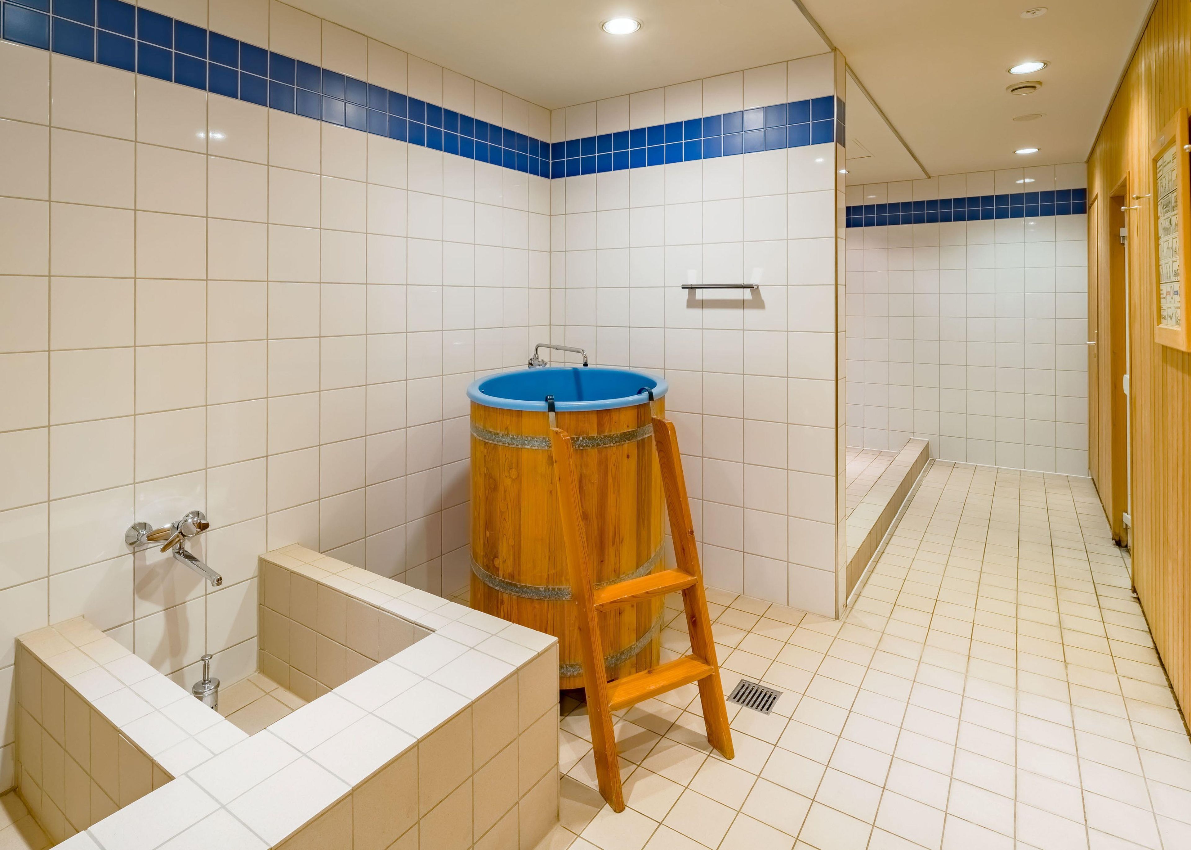 Ein Badezimmer mit weißen Fliesen, einem Holzbottich, einer Badewanne und einer Duschkabine.