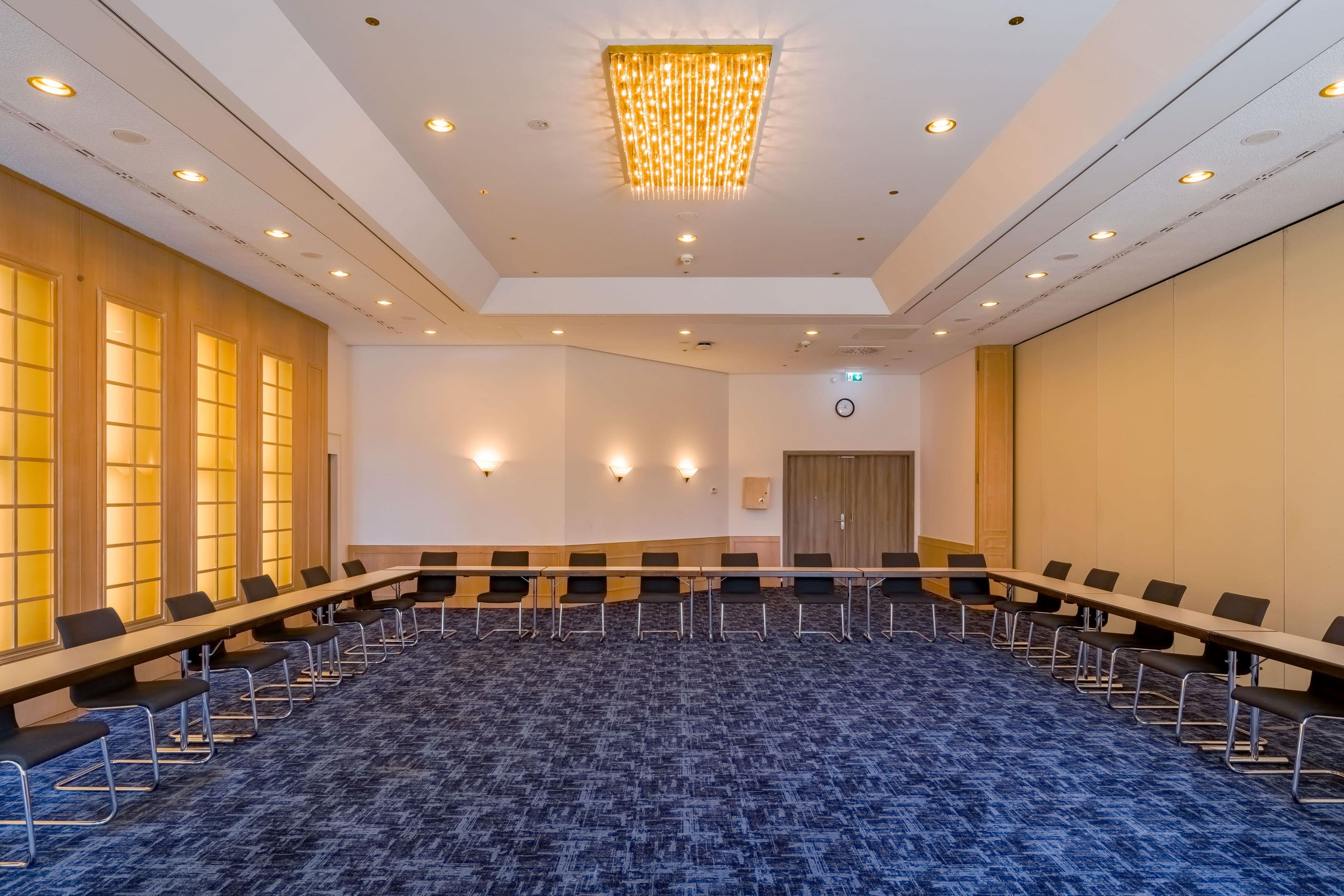 Un salón de conferencias con una mesa larga, sillas y piso alfombrado.