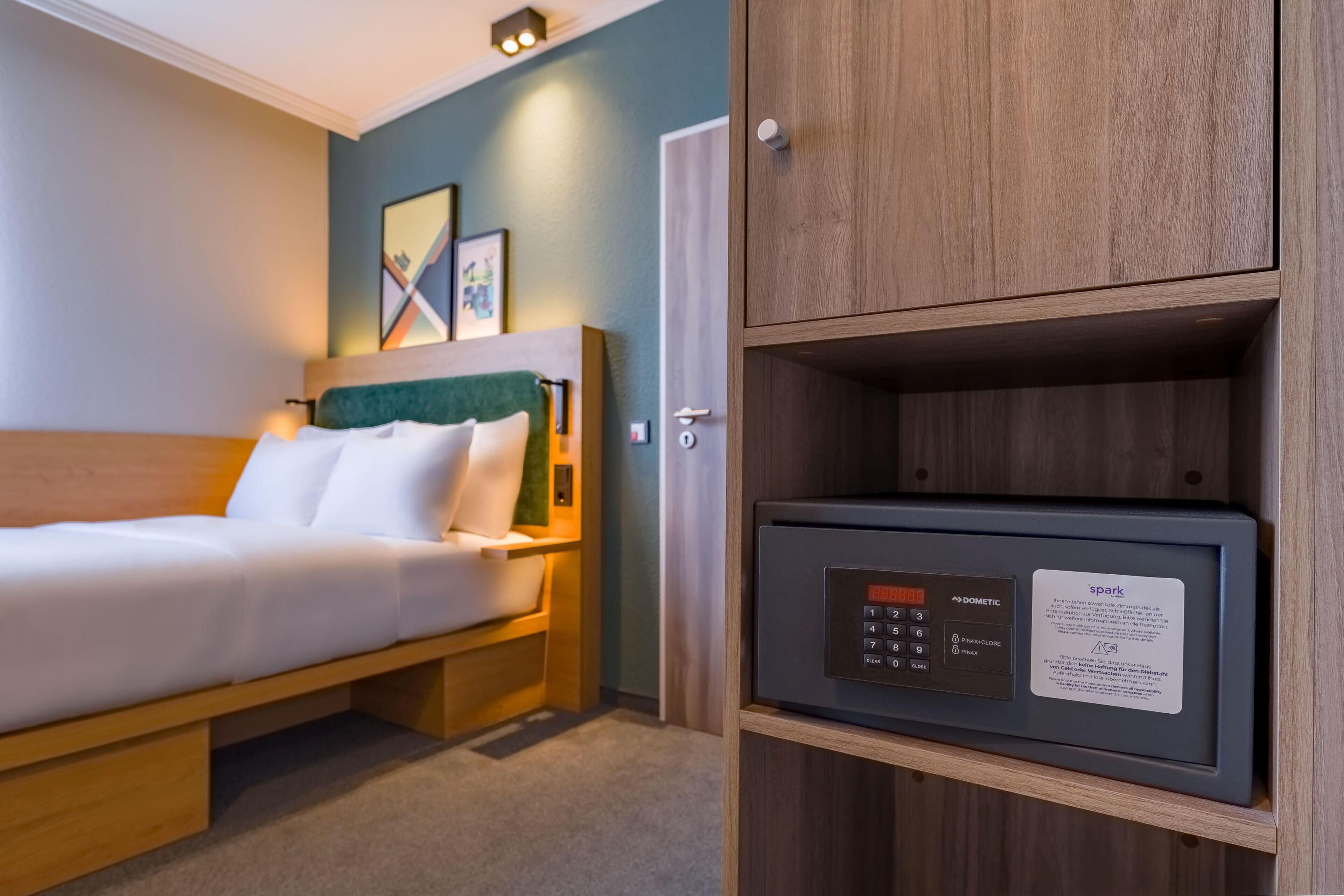 Una habitación de hotel con cama, mesita de noche, armario y panel de control.
