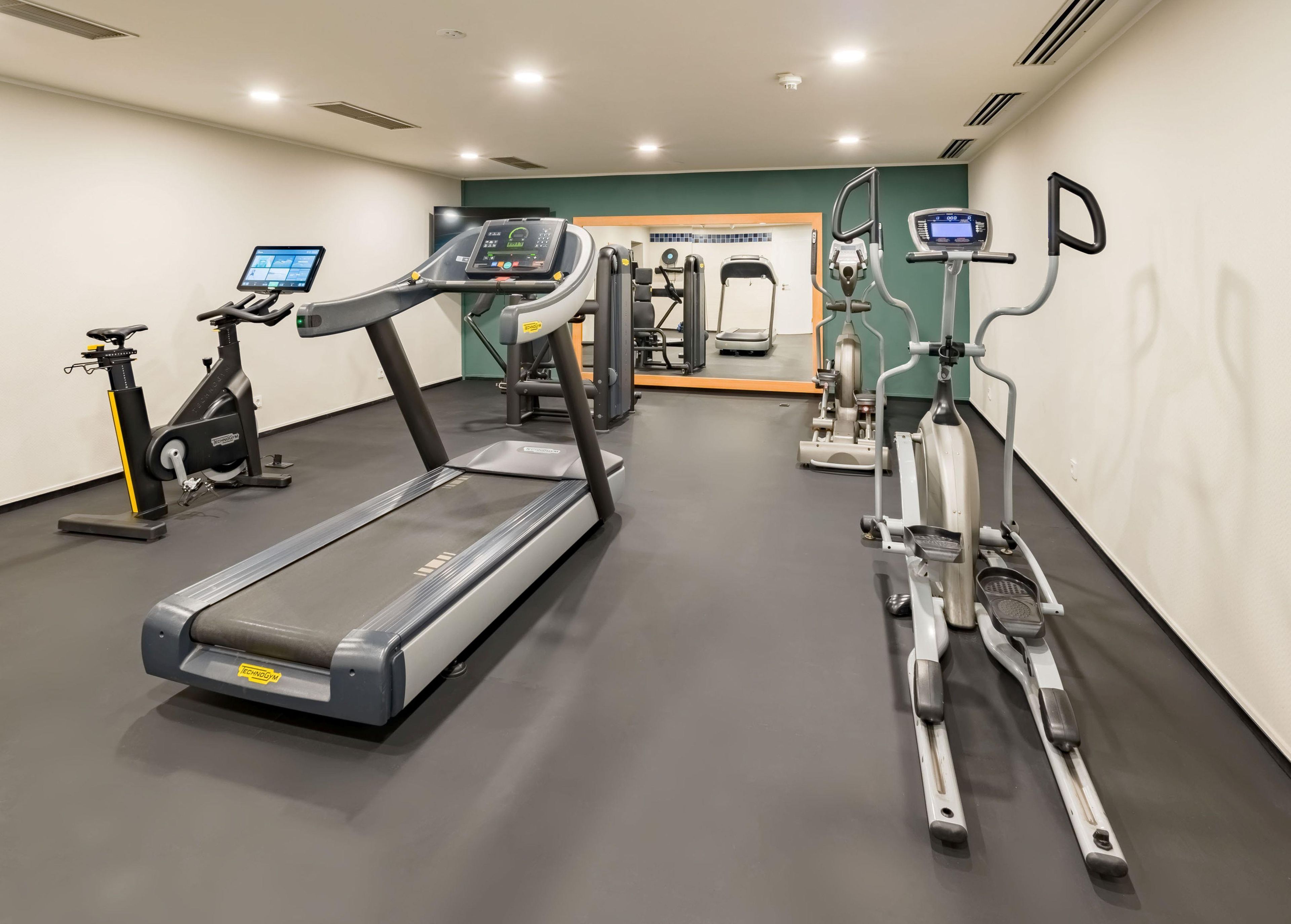 Un gimnasio con cintas de correr, elípticas y equipo de pesas.