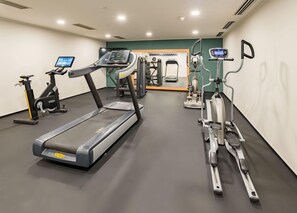 Un gimnasio con cintas de correr, elípticas y equipo de pesas.