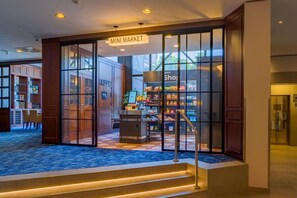 A hotel lobby with a 'Mini Market' sign, a reception desk, and a staircase leading to the upper floors. - Spark by Hilton Wuppertal City Centre (Wuppertal)