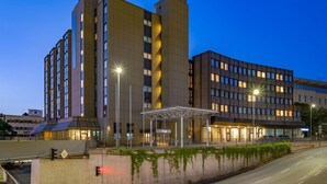 A modern hotel with a central atrium, multiple floors, and a covered outdoor area.