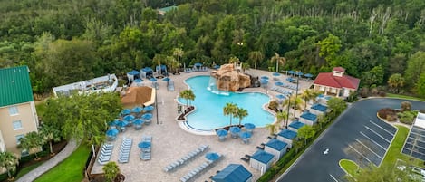 Un resort con una piscina grande, sillas de descanso y una cascada.