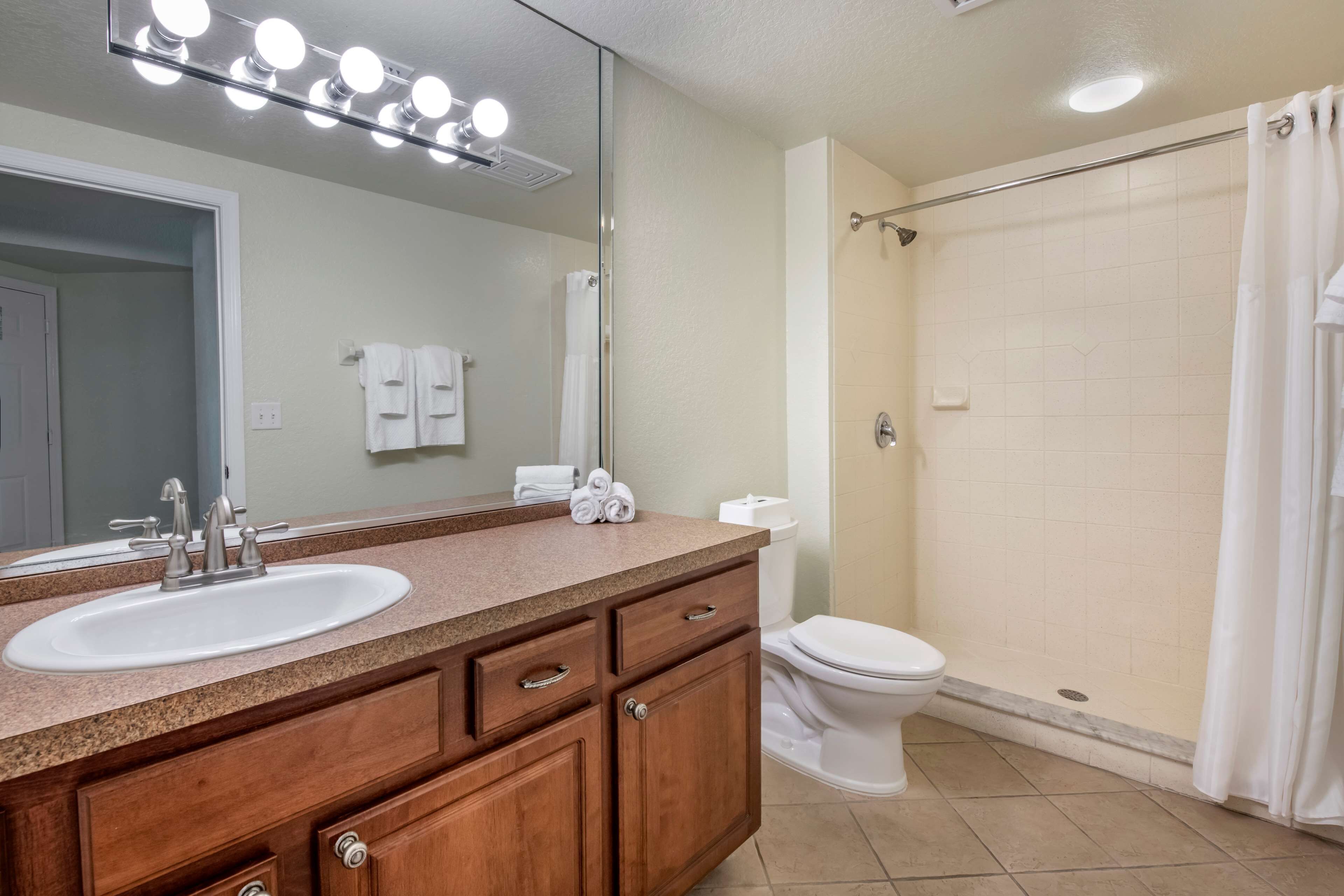 A bathroom with a sink, mirror, and shower.