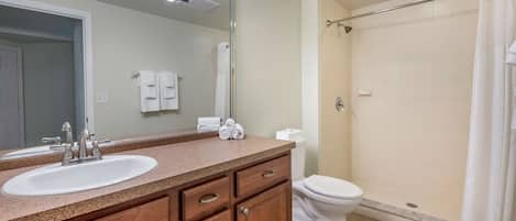 A bathroom with a sink, mirror, and shower.