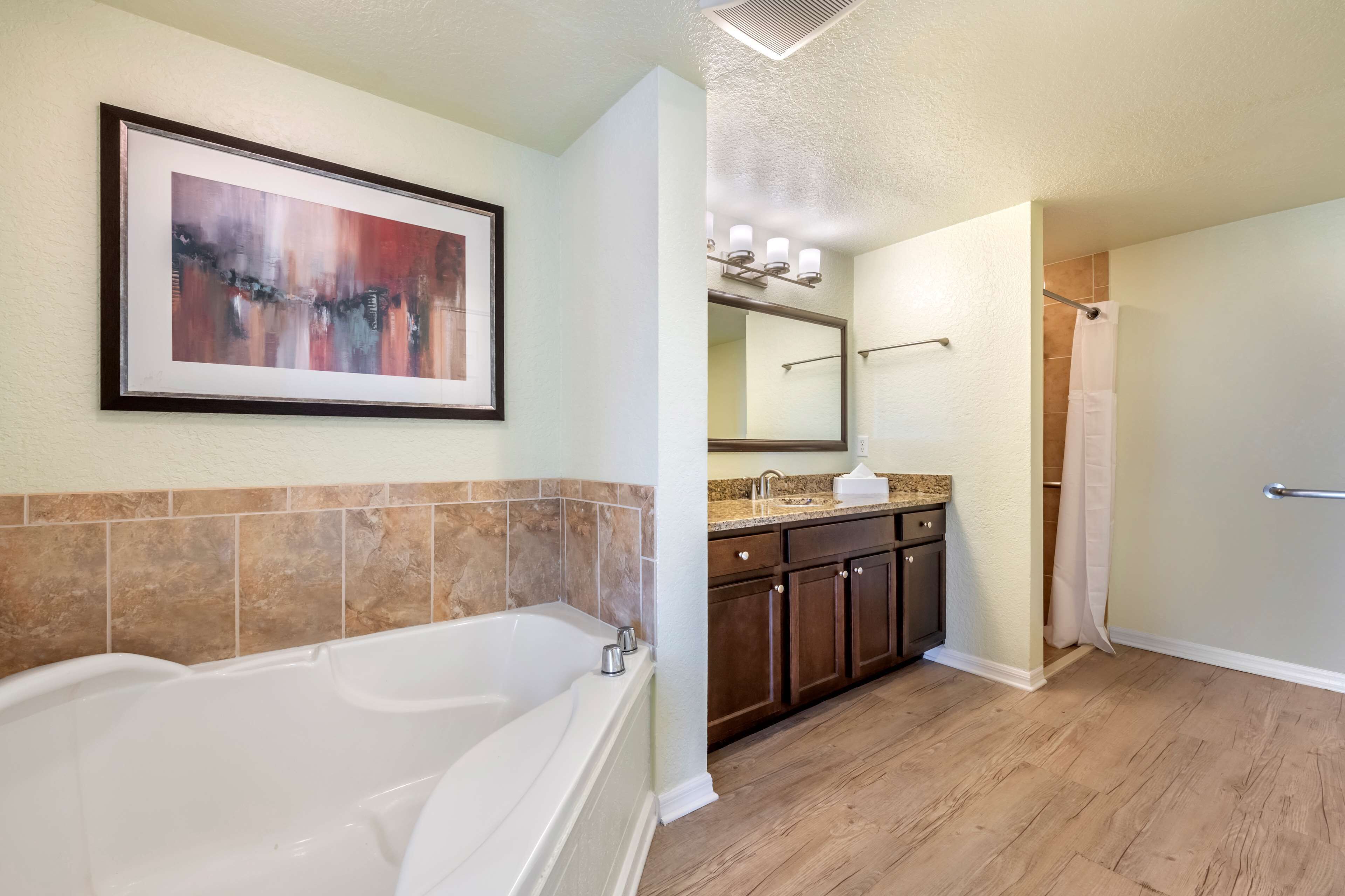 A bathroom with a bathtub, vanity with a mirror, and a shower area.