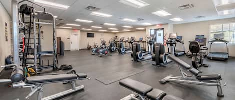A gym with various exercise equipment, including treadmills, elliptical machines, and weight machines.