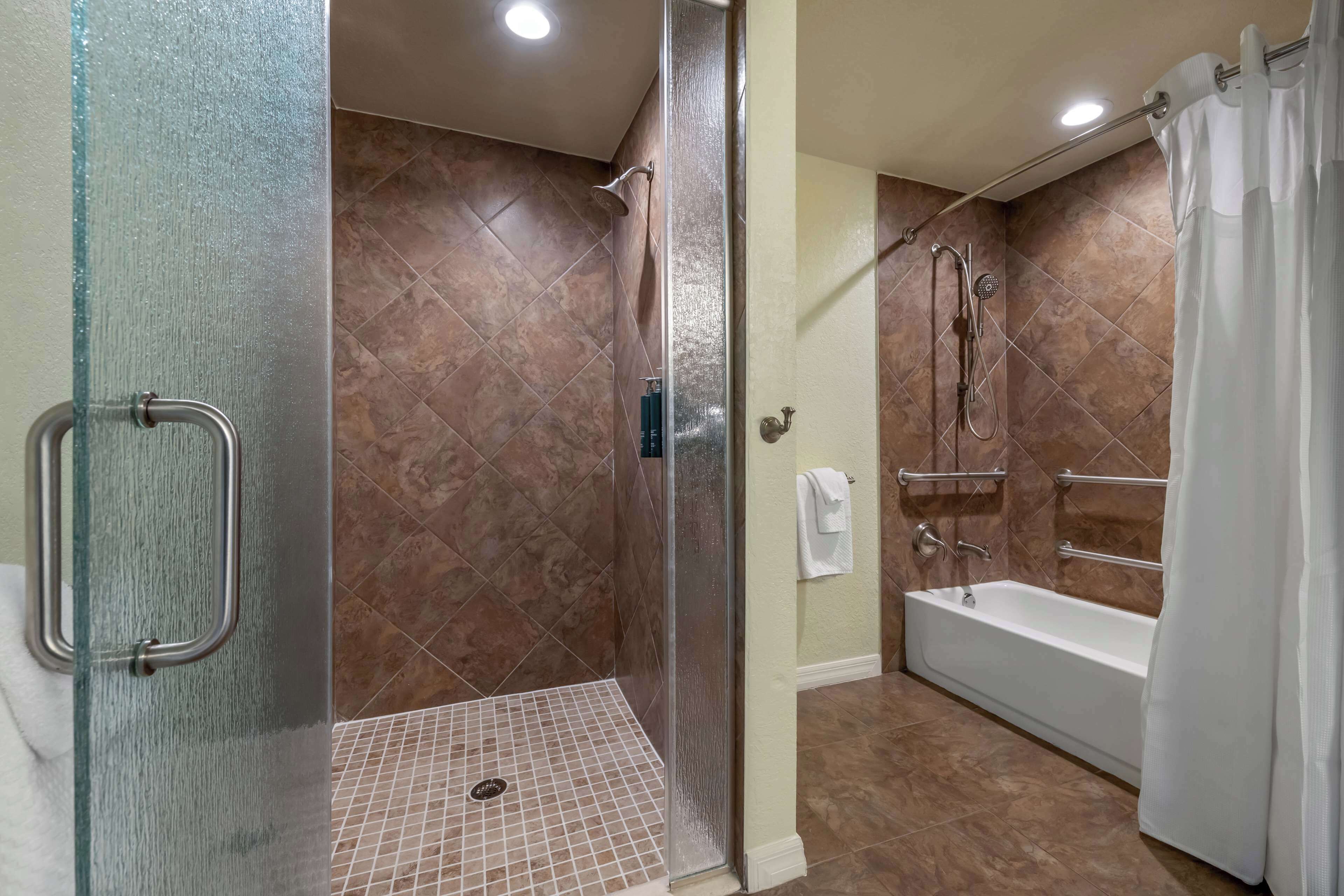 A modern bathroom with a glass shower enclosure, a walk-in bathtub, and a tiled floor.