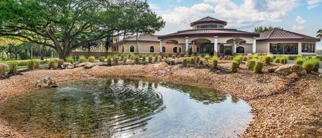A large house with a pond, surrounded by rocks and greenery.