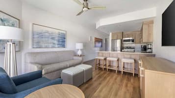 A modern living room with a sofa, ottoman, and a round coffee table.
