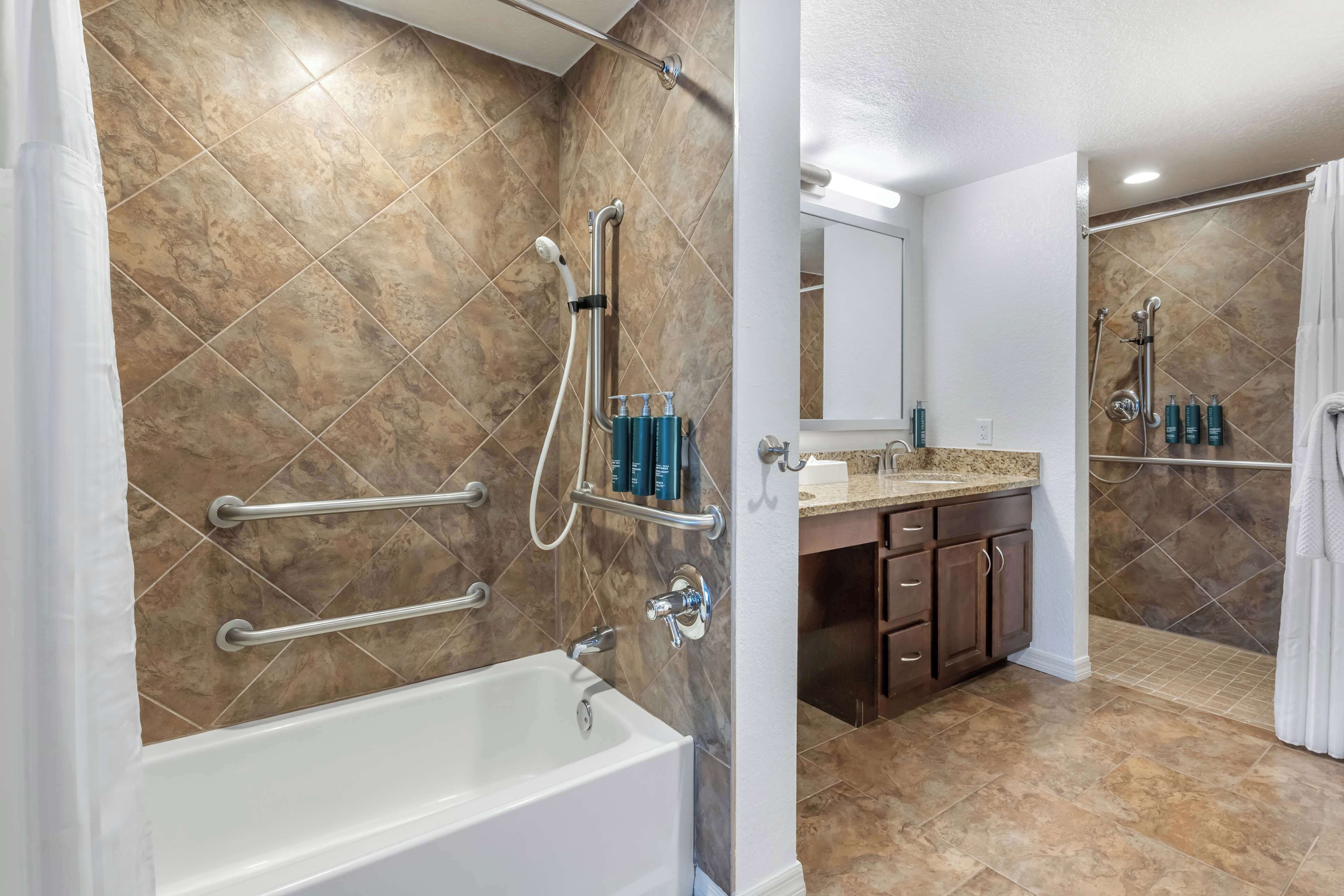 Une salle de bain moderne équipée d’une baignoire, d’une douche et d’un meuble-lavabo.