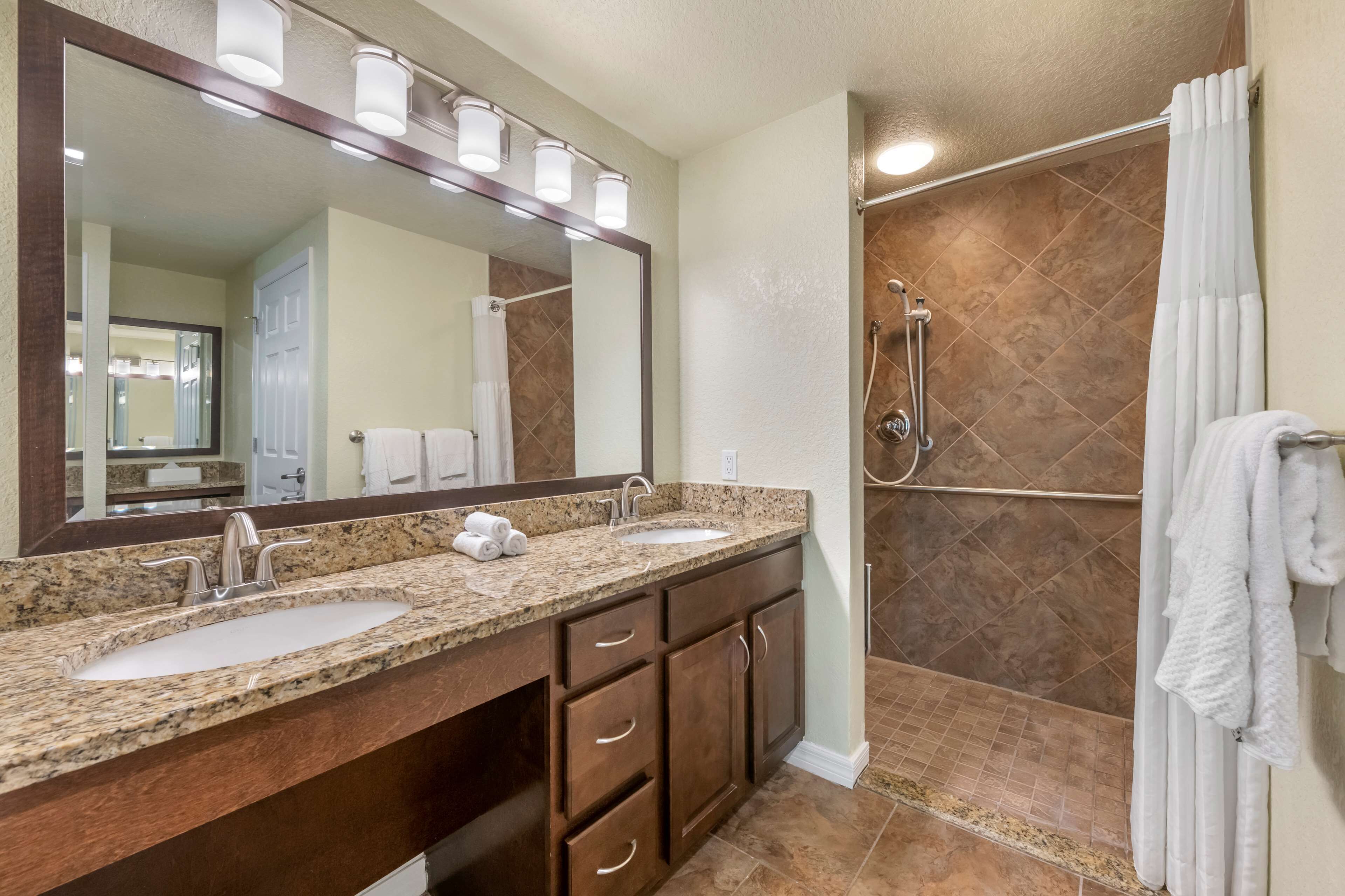 A bathroom with two sinks, a large mirror, and a shower area.