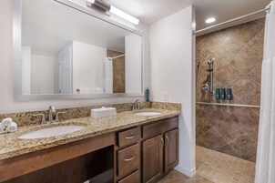 A bathroom with two sinks, a large mirror, and a shower area with a tiled wall.