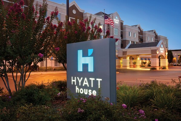 A Hyatt hotel sign with a large 'H' logo, surrounded by flowering bushes. - HYATT house Pleasant Hill (Pleasant Hill)