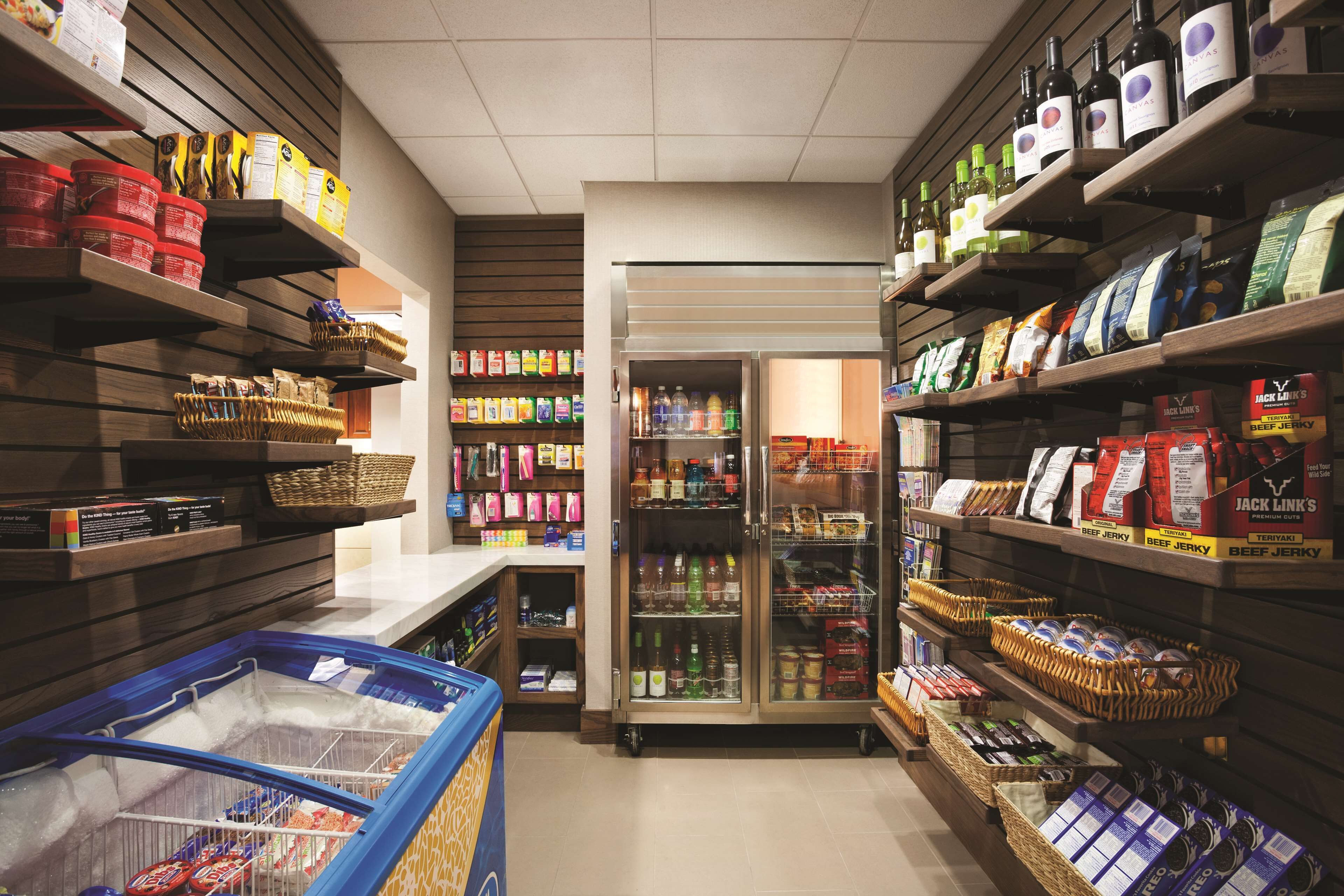 Un supermercado con estantes llenos de productos, una sección refrigerada y un congelador.