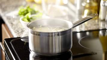 A stainless steel pot on a stove with noodles in it.