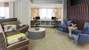 A modern hotel lobby with a sofa set, a coffee table, and a seating area with chairs and a TV. - SpringHill Suites by Marriott Austin Parmer/Tech Ridge (Austin)
