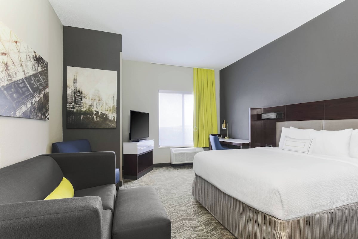 Een hotelkamer met een groot bed, een bureau met stoel, een televisie en een bank.
