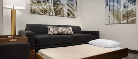 A modern living room with a sofa, a bench, a lamp, and two abstract paintings on the wall.