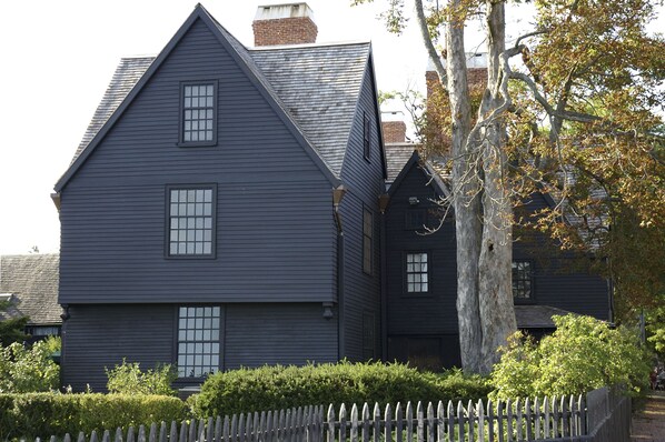 A large, dark-colored building with multiple windows and a prominent chimney.