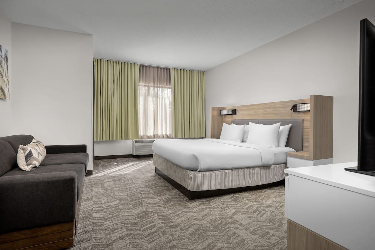 Een moderne hotelkamer met een groot bed, een slaapbank, een bureau en een televisie.