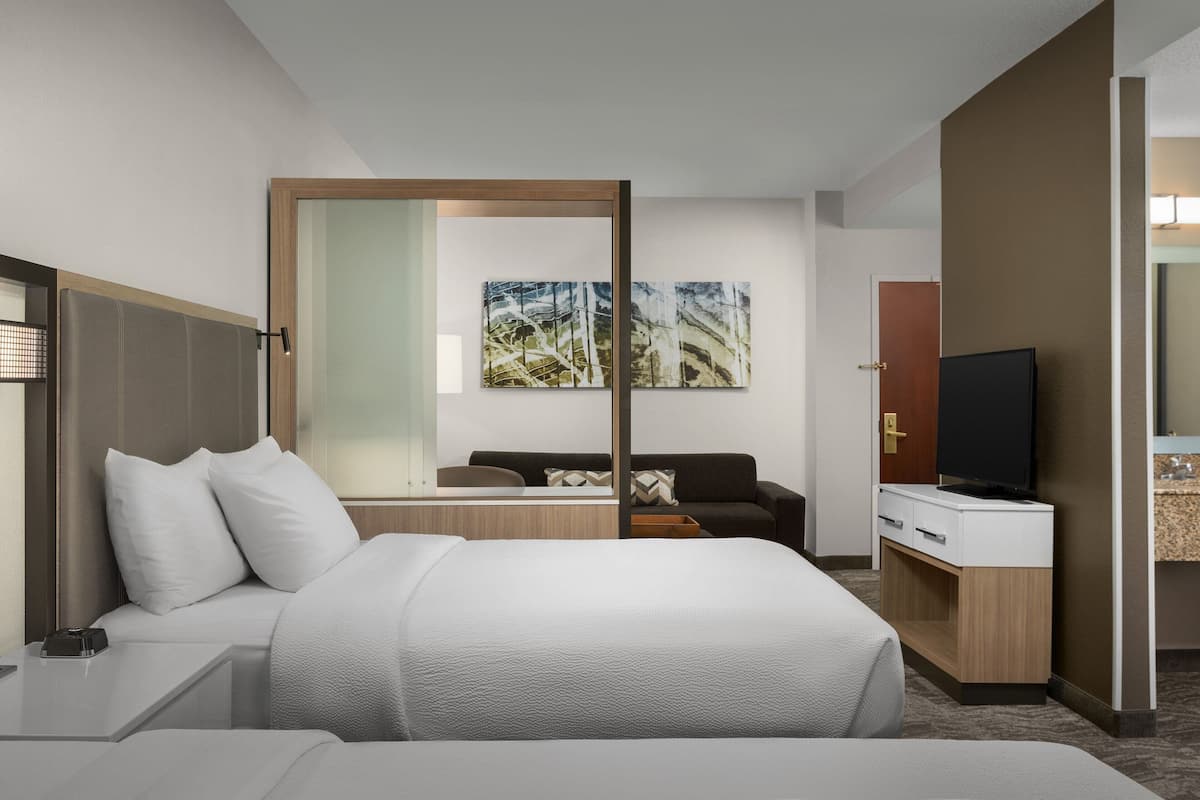 Een moderne hotelkamer met een groot bed, een bureau, een televisie en een zithoek met een bank en een salontafel.