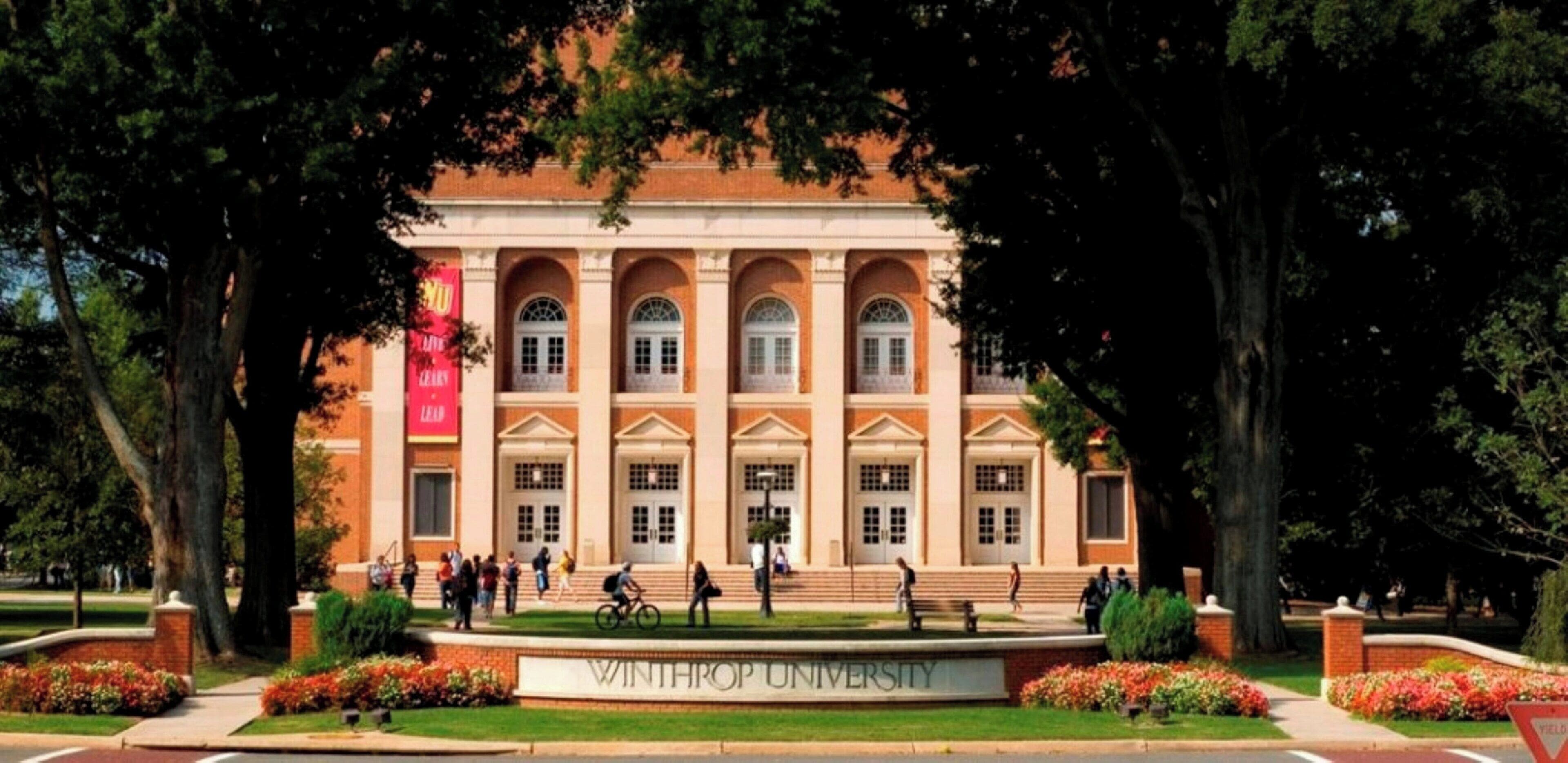 A building with a central entrance, arched windows, and a sign reading 'WINTHROP UNIVERSITY.'