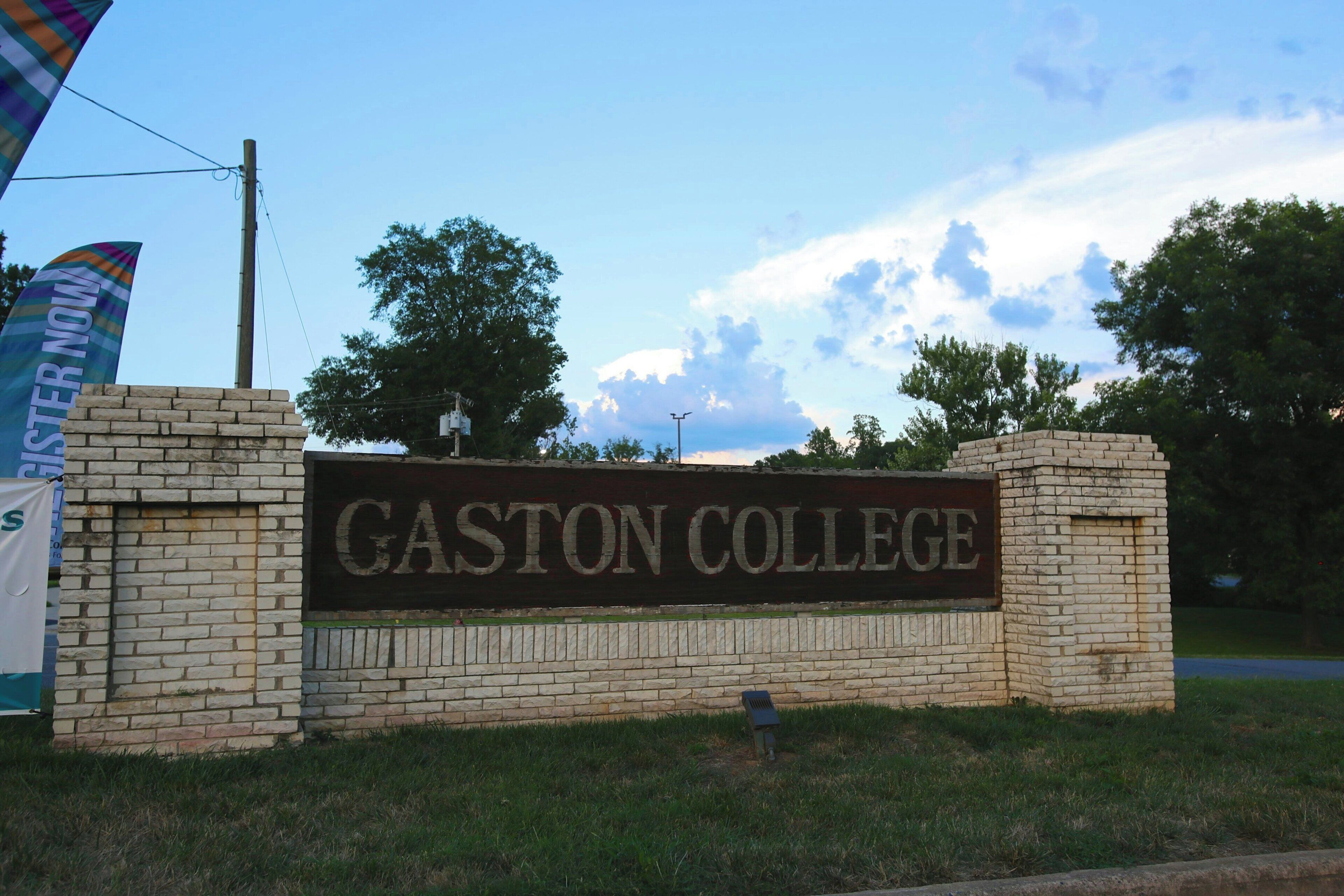 Un letrero de Gaston College con un muro de ladrillo y un cielo despejado al fondo.