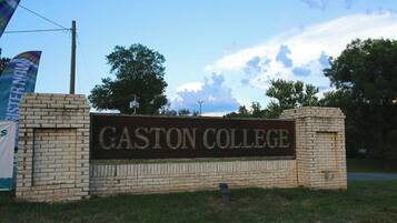 Un letrero de Gaston College con un muro de ladrillo y un cielo despejado al fondo.