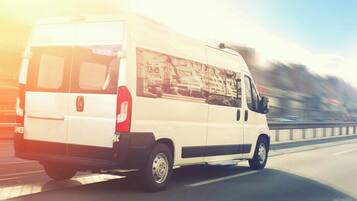 A white van driving on a highway.