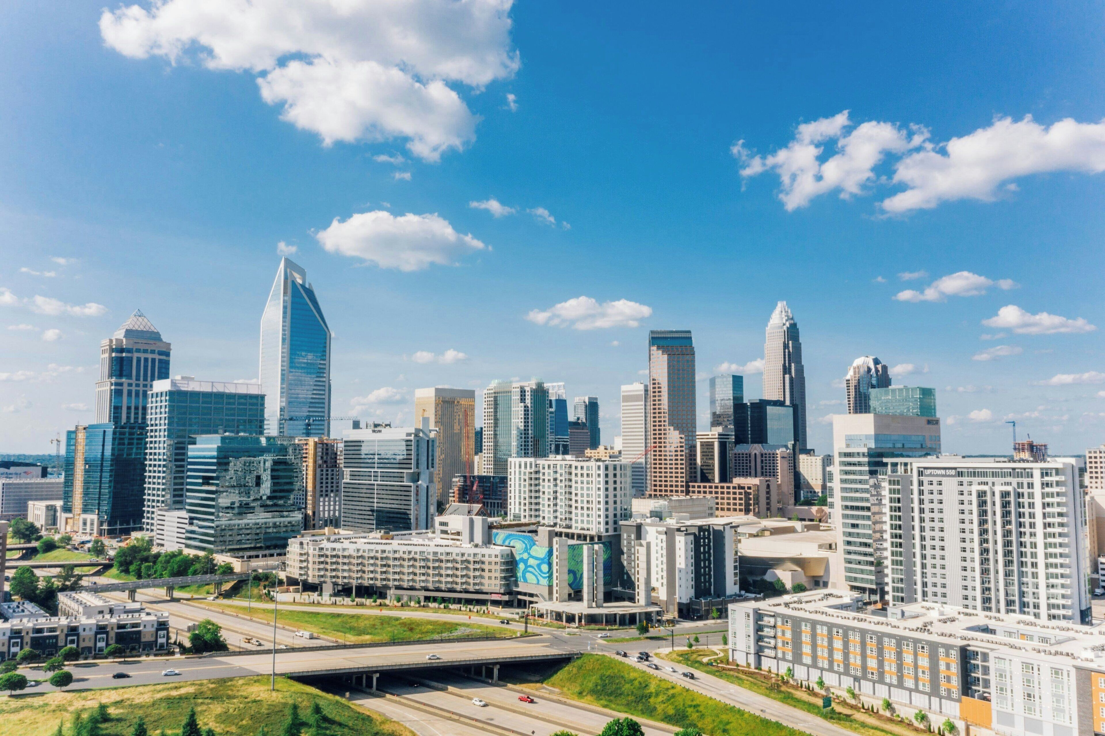 A city skyline with modern high-rise buildings, a highway, and a bridge.