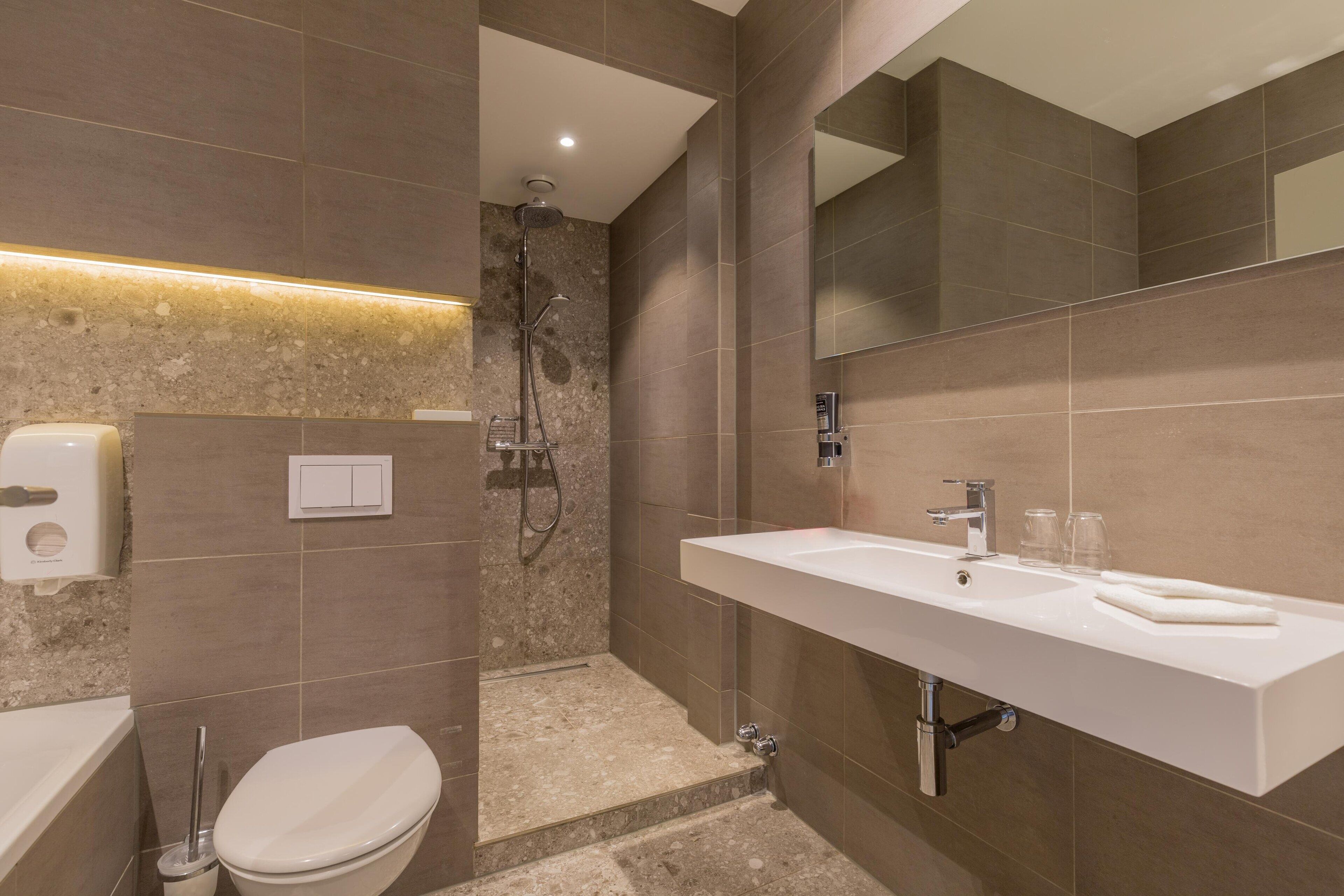 A modern bathroom with a large sink, a toilet, and a shower area.