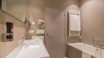 Een moderne badkamer met een groot wastafel, een badkuip en een douche. Er is een handdoekhouder en een spiegel aan de muur.