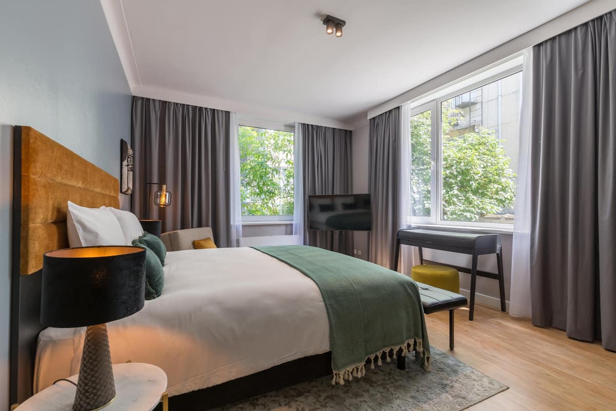 A modern hotel room with a large bed, a desk, and a TV.