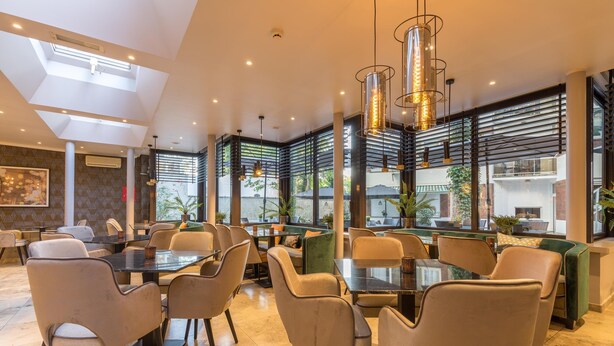 Un comedor moderno con techos altos, ventanas grandes y muebles contemporáneos.