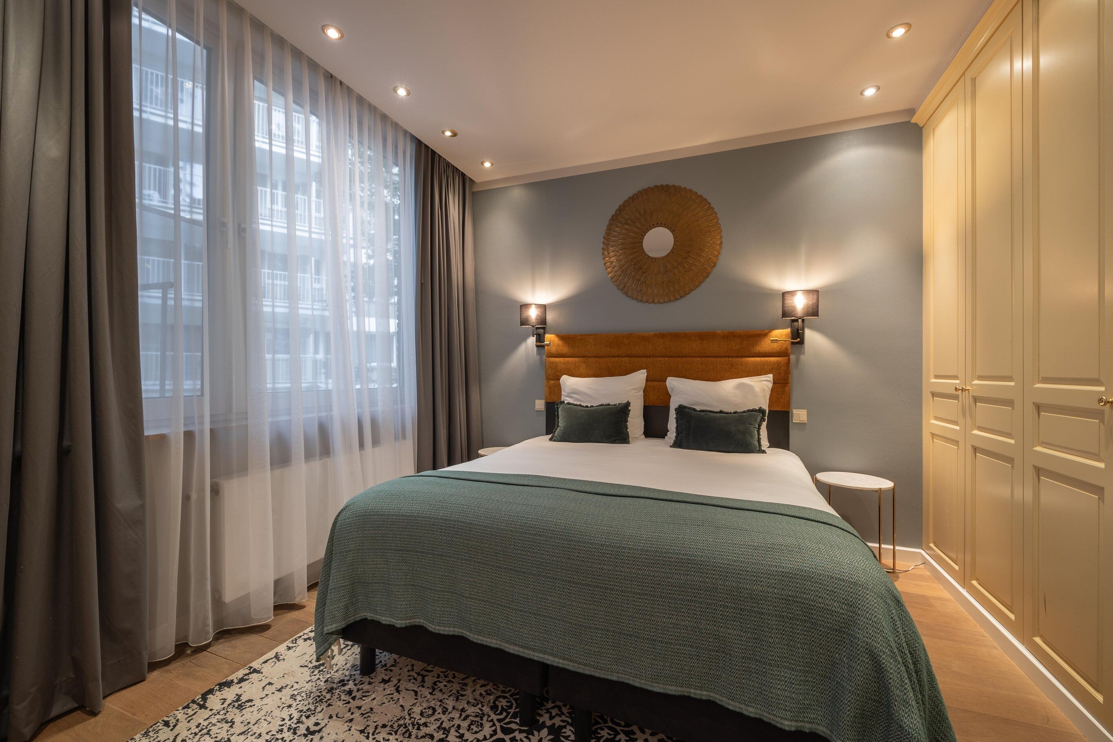 Une chambre bien rangée, avec un grand lit, un élément décoratif rond fixé au mur et une armoire.