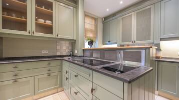 A modern kitchen with light green cabinets, a central island with a sink, and a window with blinds.